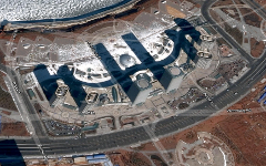 Aerial view of a complex in China with tall buildings casting long shadows, surrounded by roads (Binhe Ave, Aimin Rd, Wenming Rd, Longitude 4th Rd) and circular architectural elements.