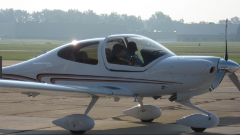 A white Diamond Star XLS airplane is on the tarmac, with two people visible in the cockpit.