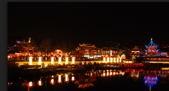 Night view of a Chinese town with illuminated traditional buildings reflecting in the water.