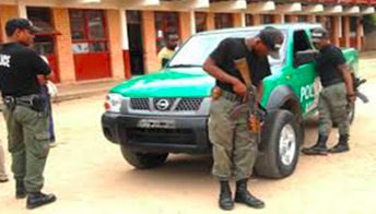 Certainly! Here's a description of the image within the character limit:The image shows several armed police officers, wearing dark uniforms and boots, standing around a green and black police vehicle in Madagascar.