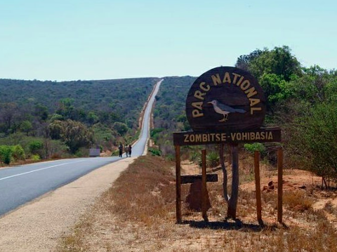 A road stretches into the distance next to the Zombitse-Vohibasia National Park sign in Madagascar.