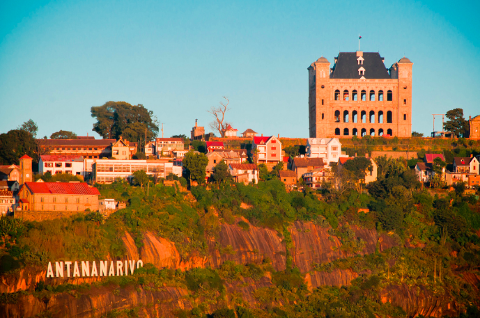 A captivating view of Antananarivo, Madagascar, showcasing the Queen's Palace atop a hill dotted with buildings and lush greenery.