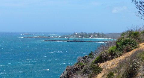 This is a scenic view of Madagascar's 3 Bays, with turquoise water, rocky islets, and a coastline of dunes and vegetation.