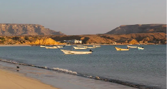 Barcos parados em uma baía perto de uma praia e colinas na Somália, criando um cenário costeiro sereno.