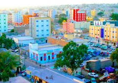 A colorful cityscape with various buildings, cars, and trees under a bright sky, possibly in an urban environment.