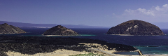 A panoramic view showcases the beauty of Djibouti's coastline, with a black rocky shoreline contrasting with the blue waters and several dome-shaped islands dotting the horizon.