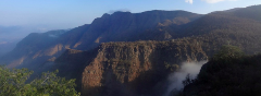A panoramic view of rugged mountains in Djibouti, shrouded in a soft haze and partial cloud cover, showcasing the country's diverse landscapes.