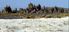 A landscape of white rocky ground leads to a rocky ridge with unique formations under a clear sky.