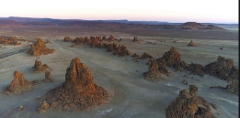 This is a wide landscape shot of Lake Abbe, Djibouti, featuring numerous limestone chimneys rising from the dry, salty plain.