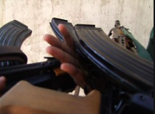 Here is a one-sentence description of the image:The image shows a person holding an AK-47 rifle, with two magazines attached to it.