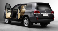 A dark gray Toyota Land Cruiser SUV is shown with its driver and rear passenger doors open, revealing a light beige interior.