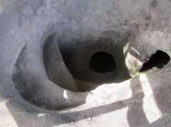 A close-up view shows two dark, irregular holes in a textured, light-colored surface, casting shadows.