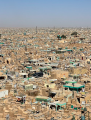 An aerial view shows a vast expanse of tombs and structures covering a landscape under a clear sky.