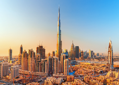 A panoramic view of the Dubai skyline features a majestic Burj Khalifa as its centerpiece, set against a blue and golden sky at sunset.