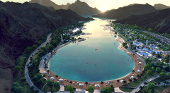 An aerial view of a lagoon surrounded by mountains and a resort area with beaches, pools, and tent-like structures.