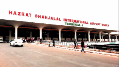 A daytime shot of Hazrat Shahjalal International Airport Dhaka Terminal-1 shows people walking on the sidewalk and a white car driving on the road.