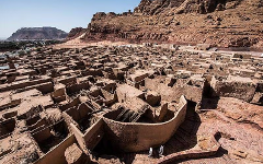An aerial view showcases the Al-'Ula old town's mud-brick architecture in Saudi Arabia, with rugged mountains in the backdrop.