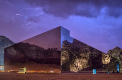 A stunning shot captures a modern mirrored building reflecting a dramatic desert landscape under a stormy sky with lightning.
