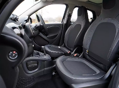 The interior of a Smart car is visible, featuring black leather seats with light gray stitching, a compact dashboard, and a sunroof, conveying a modern and minimalistic aesthetic.