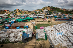 An overview of a densely populated settlement with many small, colorful buildings spread across a hilly landscape under an overcast sky.