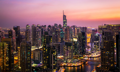 A mesmerizing cityscape of Dubai's skyline at dusk, featuring numerous illuminated skyscrapers and waterways under a colorful sky.
