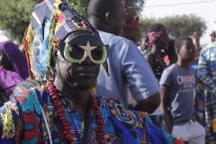 A man with colorful attire and star-shaped sunglasses at an outdoor event.