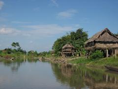 A serene view of a river village in Papua New Guinea with traditional stilt houses under a blue sky.