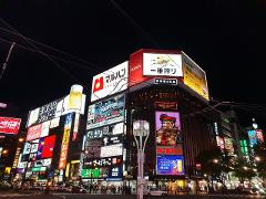 The bustling nightlife of Sapporo, Japan is captured with vibrant neon signs illuminating the Susukino district.