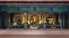 A serene view of a Japanese Buddhist altar within a temple, showcasing intricate details, traditional drums, and ornate decorations bathed in soft, golden light.