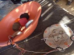 A craft project is underway with a woven basket and a container filled with yarn, all resting on a weathered wooden surface.