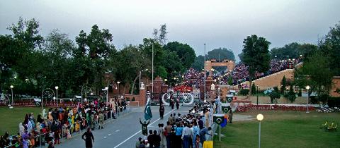 A large crowd gathers at the Wagah border ceremony between India and Pakistan, with spectators lining the roadside and filling the stadium seating.