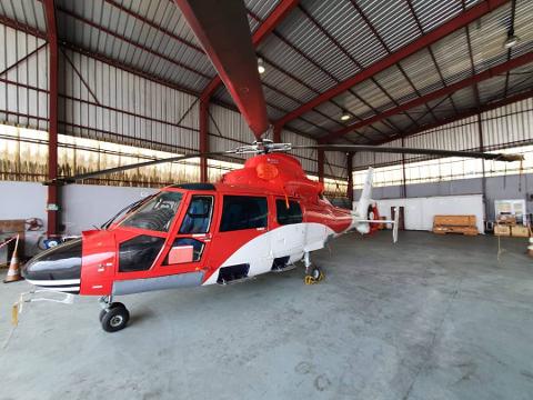 A red and white helicopter is parked inside a hangar.