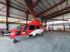 A red and white helicopter is parked inside a hangar.
