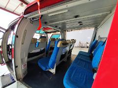 Interior view of a helicopter cabin with rows of blue seats, ready for passengers on shore excursions from Libreville.