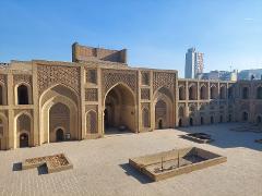 A wide shot depicts the historic Al-Mustansiriya University in Baghdad with its patterned brickwork and courtyard under a clear sky, juxtaposed against a modern high-rise in the background.