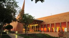 A wide shot shows the King Abdulaziz Center for World Culture in Dhahran, Saudi Arabia. It features a distinctive geometric design and a landscaped exterior.