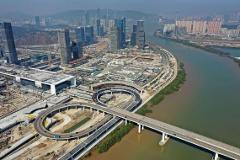 Aerial view of a city with skyscrapers and a river with a bridge and highway interchange.