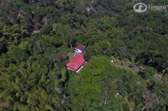 Birding - Cali, Coffee Region & Medellin An aerial shot captures a red-roofed building and a blue structure nestled within lush green foliage, possibly in a tropical or mountainous area.