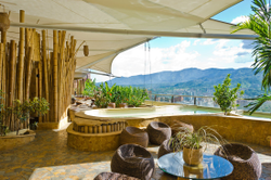 Birding - Cali, Coffee Region & Medellin An inviting outdoor terrace features natural materials like bamboo and stone, with comfortable seating overlooking a scenic mountain view and a pool.