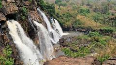 Bangui short city travel package including visa on arrival for Central African Republic A majestic multi-tiered waterfall cascades down rugged, rocky cliffs amidst lush green vegetation.
