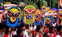 A crowd of people carrying colorful, ornate owl masks during a festival or parade, creating a vibrant and festive atmosphere.