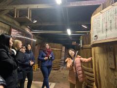 Samurai Miso Soup Making Experience in Nishio Aichi A diverse group of people is touring a historic miso factory, examining large wooden vats and informational displays.