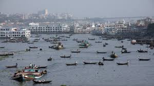 Here's a description of the image:This image captures a busy river scene in Dhaka, Bangladesh, filled with numerous small boats and ferries, with a cityscape visible in the background.