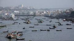 Here's a description of the image:This image captures a busy river scene in Dhaka, Bangladesh, filled with numerous small boats and ferries, with a cityscape visible in the background.