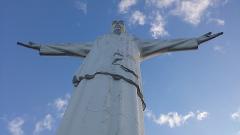 Cali City Tour A low-angle shot of a white statue of Jesus Christ with outstretched arms against a blue sky with scattered clouds.