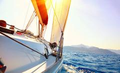 Sailing the Caribbean in Colombia A sailboat glides across the sea under a clear sky, with the coastline faintly visible in the distance.