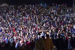 Certainly! Here's a description of the image within the character limit:A large crowd of people, possibly at the Agadez African Music Festival, is packed together, viewed from an elevated perspective with stage lights illuminating the scene.
