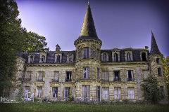 Central African Republic 4-Day Adventure Tour An aged, grand chateau with towering turrets stands amidst overgrown greenery under a twilight sky.