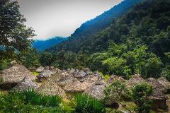 Lost City Trek Sierra Nevada Expedition (4 Days / 3 Nights) A village of thatched-roof indigenous homes nestled at the base of a lush, green mountain under a cloudy sky.
