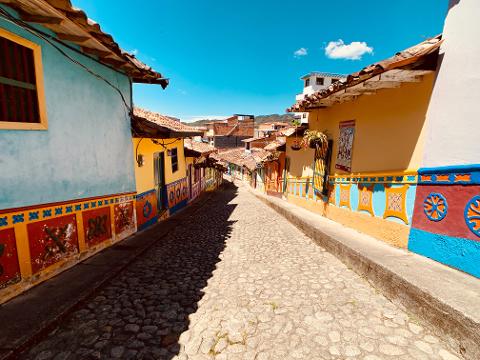 A vibrant cobblestone street lined with colorful colonial buildings under a bright blue sky, showcasing a picturesque and inviting scene.